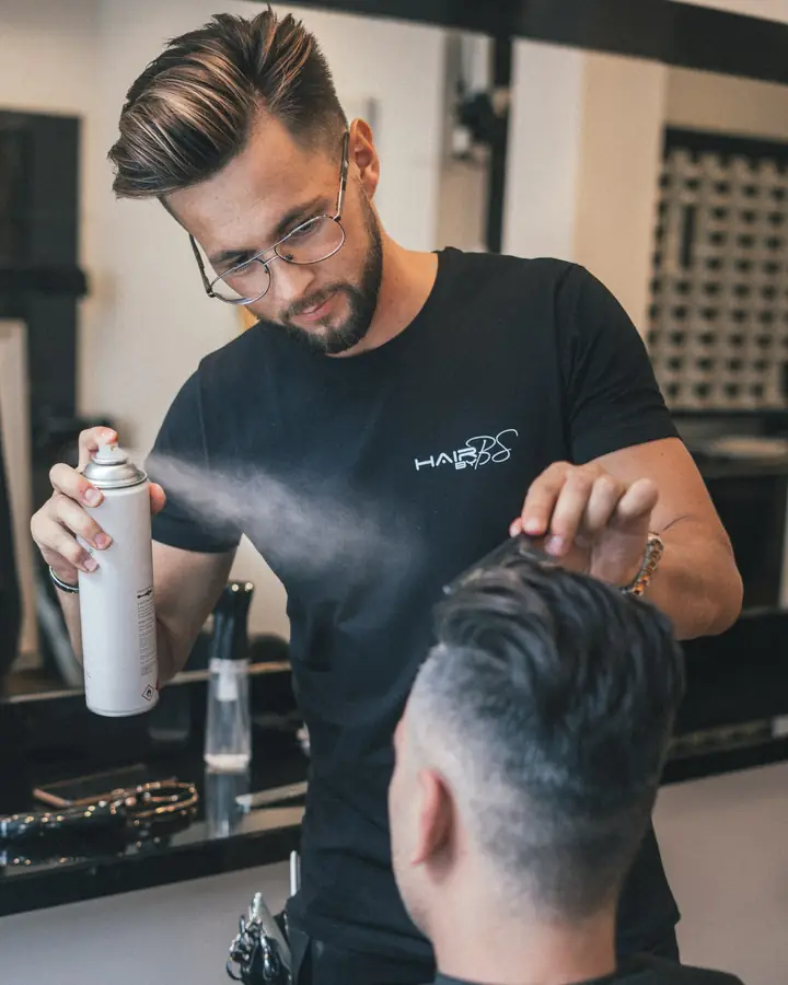 Barber menyemprotkan hair spray ke rambut pelanggannya