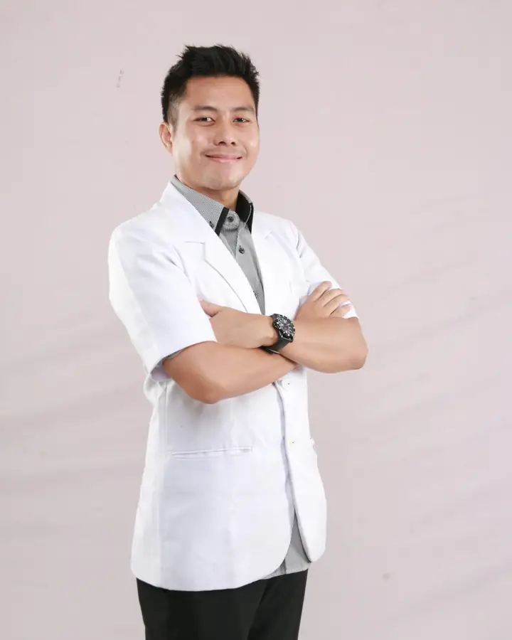 Dokter muda berjas putih bersedekap